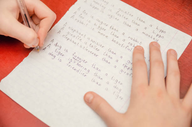 istock girl does a task in English, writes in a notebook close-up 1213241627