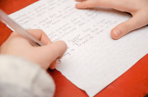 istock girl does a task in English, writes in a notebook close-up 1213241726