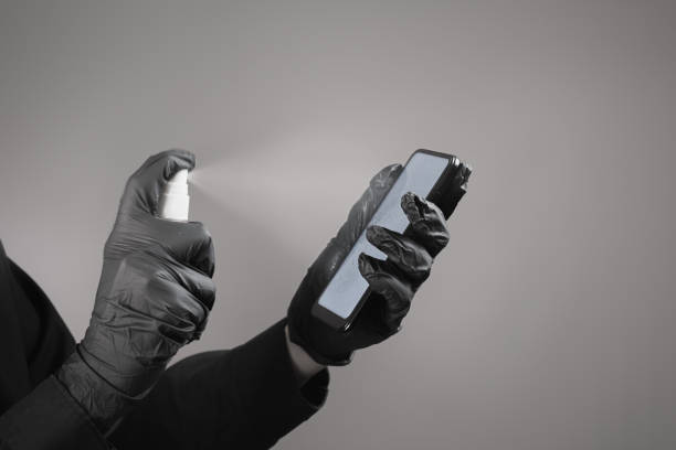 istock Cleaning the phone with a sanitizer, total black concept. 1213242350
