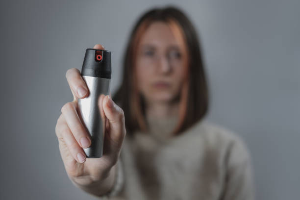 mujer con un spray de pimienta, fondo discreto. - pulverizador de pimienta fotografías e imágenes de stock