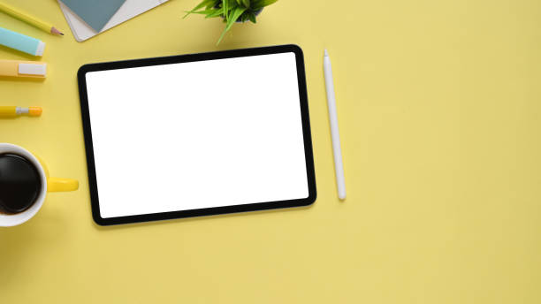 istock Top view image of colorful working table with accessories putting on it. Flat lay Computer tablet with white blank screen, stylus pen, marker pen, notebook, diary, coffee cup and potted plant. 1213244038