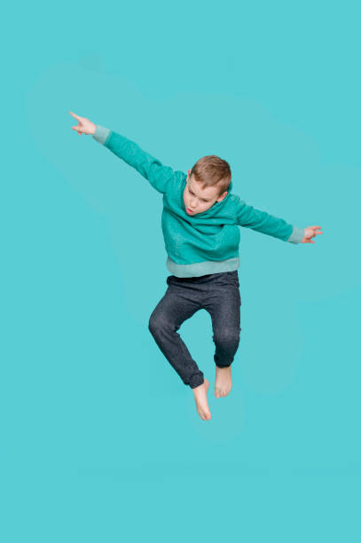 istock Adorable little boy jumping, isolated on blue background. Shooting in the studio. 1213244256