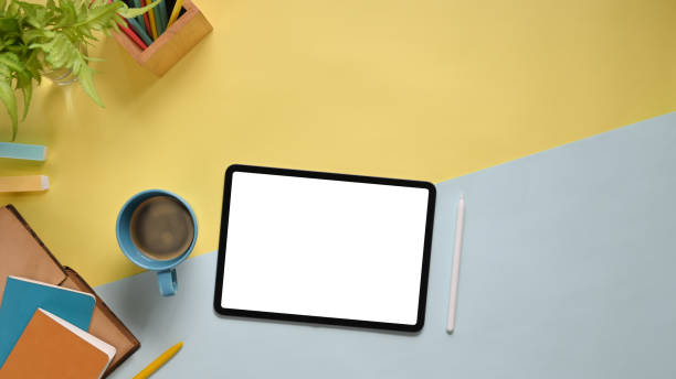 istock Top view image of colorful working table with accessories putting on it. Flat lay Computer tablet with white blank screen, stylus pen, marker pen, notebook, diary, coffee cup and potted plant. 1213244391