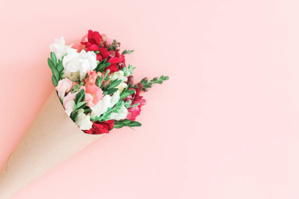 istock Roses bouquet in cone on pink background, flat lay, top view. 1213248116