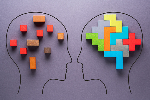 The concept of rational and irrational thinking of two people. Heads of two people with colourful shapes of abstract brain for concept of idea and teamwork on gray background. Different thinking.