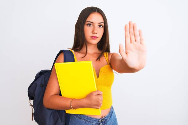 istock Beautiful student girl wearing backpack holding notebook over isolated white background with open hand doing stop sign with serious and confident expression, defense gesture 1213249906