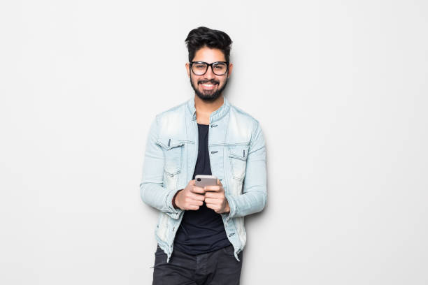 istock Young handsome Indian bearded man using mobile phone isolated on white background 1213256921