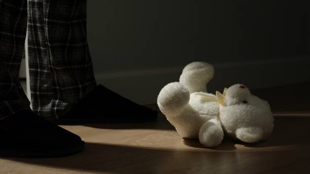 istock Man looks at Small Plush Bear Toy Up At Home 1213257347