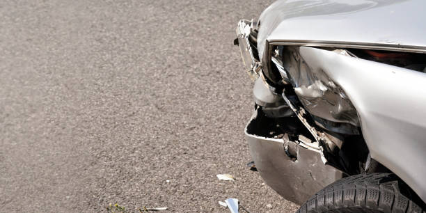 istock Crashed silver car, detail on front broken bumper and tire, space for text left side 1213258467