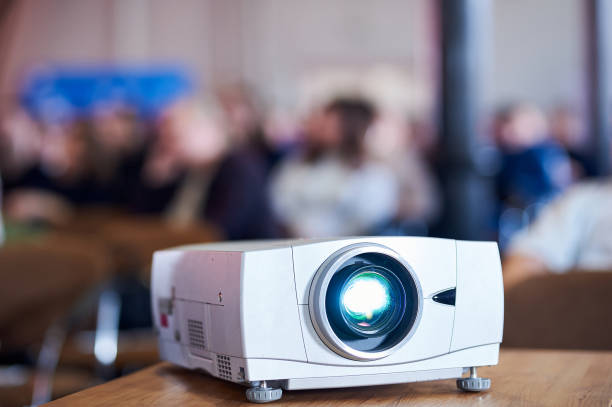 istock Close-up multimedia projector with blurred people background 1213258811