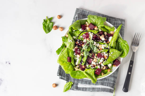istock Beetroot, spinach, chickpea, feta cheese and hazelnut salad decorated with sprouts on light kitchen table. Copy space for text. Top view. 1213260916