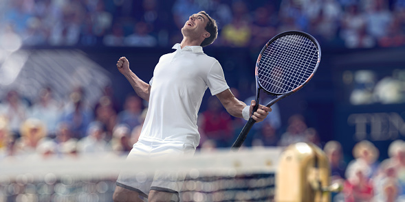 A close up of a professional tennis player dressed in tennis whites, holding racket up with fists clenched, looking updates with mouth open celebrating victory. The athlete playing in a generic tennis arena full of spectators with the tennis net in the foreground and spectators . With shallow depth of field.