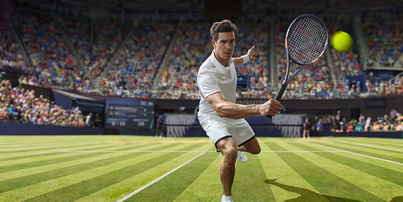 A close up of a professional male tennis player in mid motion with racket forward, about to hit the ball in a backhand volley. The athlete is dressed in tennis whites and plays in a tennis match on grass in a generic stadium full of spectators on a bright sunny day.