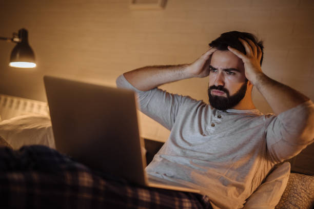 istock Upset young man working late in bed on a laptop 1213270519