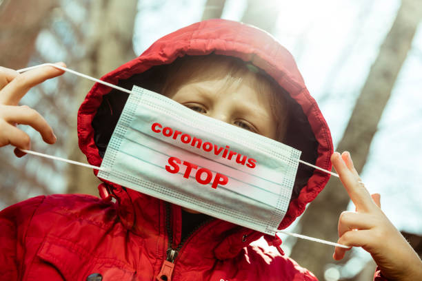 istock Little Boy holding protective mask with inscription Stop Coronavirus 1213270526