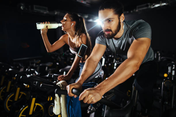 istock Two young people exercising on exercise bike at gym 1213272379