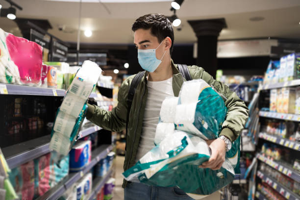 The most important thing is to make a stock of toilet paper! Young Man shopping in a supermarket, breathing through a medical mask because of the danger of getting the flu virus, influenza infection. Corona virus pandemic concept. Covid-19 virus! toilet paper photos stock pictures, royalty-free photos & images