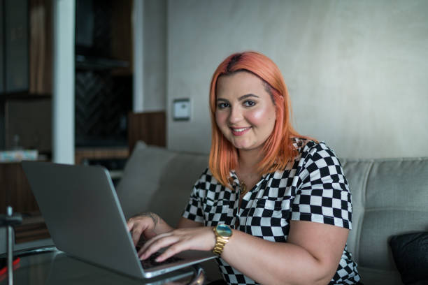 Portrait of young woman using laptop at home Portrait of young woman using laptop at home lgbtqcollection stock pictures, royalty-free photos & images