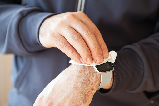 man hands disinfecting smart watch, eliminating germs coronavirus bacteria