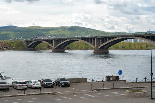 View of the Communal Bridge (1961) and the pier with parked cars from Dubrovinsky Street from the left bank. Krasnoyarsk, Krasnoyarsk Territory / RF - May 22, 2019: View of the Krasnoyarsk Communal Bridge (1961) and the pier with parked cars from Dubrovinsky Street from the left bank. krasnoyarsk krai photos stock pictures, royalty-free photos & images