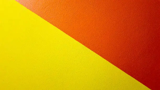 Red and yellow painted wall texture abstract grunge background with copy space. Abstract geometric pattern on the wall. The wall is divided into borders of different colors.