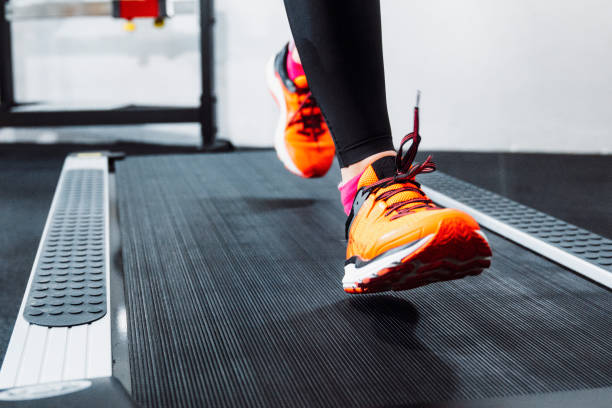 Unrecognizable female athlete running on a treadmill Close up of a person jogging on a treadmill in fitness center. Warming up with some cardio training. training equipment stock pictures, royalty-free photos & images