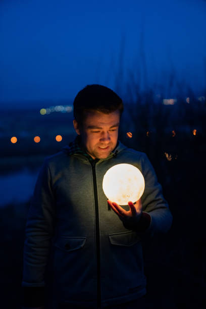 istock man in gray sweater holds full moon in dark 1213290946