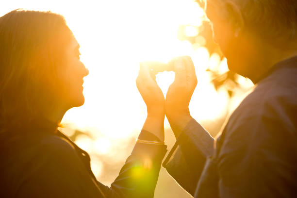 Silhouette of couple making heart shape with their hands at park
