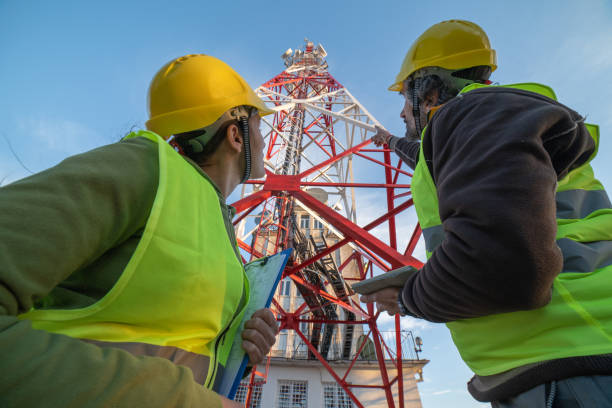 Engineers working on the field near a Telecommunications tower. Teamwork.