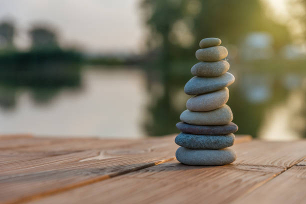 zen balancing pebbles next to a misty lake - aspirations pebble balance stack imagens e fotografias de stock