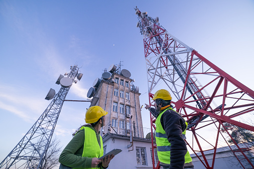 Ingenieros trabajando en el campo cerca de una torre de telecomunicaciones. Trabajo en Equipo. photo