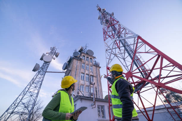 inżynierowie pracujący na polu w pobliżu wieży telekomunikacyjnej. pracy zespołowej. - telecommunications equipment zdjęcia i obrazy z banku zdjęć