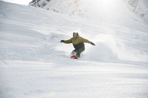 istock Snowboarder in anorak rides on a snowboard in mountains 1213297778