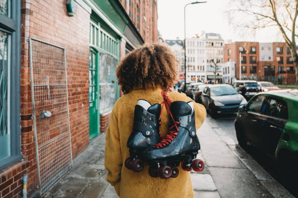 jovem caminhando na cidade segurando patins - patins em linha - fotografias e filmes do acervo