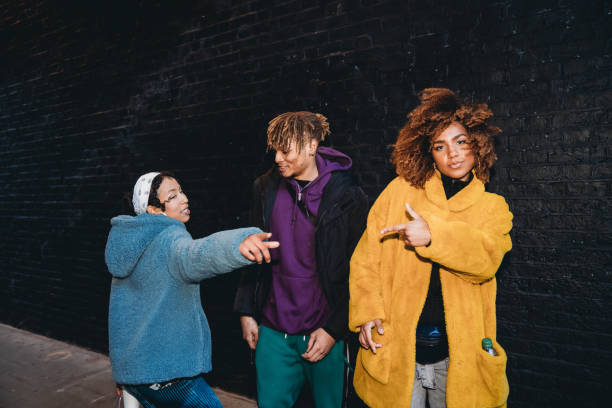 drei freunde tanzen in der stadt gegen eine schwarze backsteinmauer - hip hop hipster afro men stock-fotos und bilder