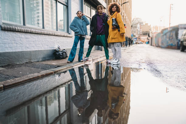 Three hip friends reflected in a puddle in the city