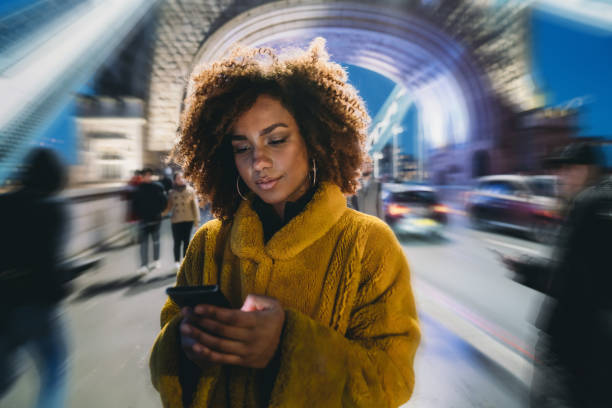 hip młoda dorosła kobieta za pomocą smartfona w mieście na tower bridge - london england england street light telephone zdjęcia i obrazy z banku zdjęć