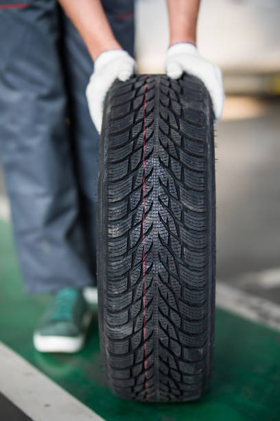 istock Auto mechanic carrying tire in tire store 1213300874