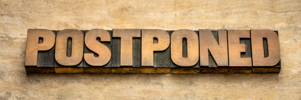 postponed word abstract in wood type postponed  - word abstract in vintage letterpress wood type, event postponement due to covid-19 coronavirus pandemic, social distancing concept printing block photos stock pictures, royalty-free photos & images