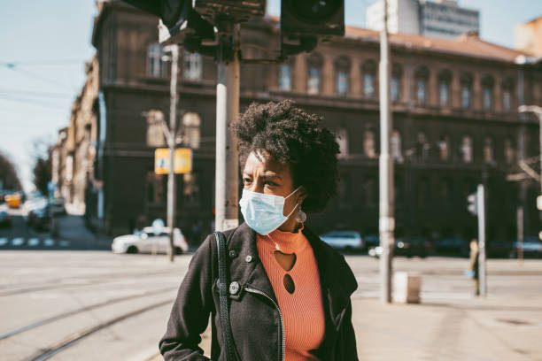 Portrait Of Young Woman With Mask On The Street. Young Afro American woman standing on city street with protective mask on her face. Virus pandemic and pollution concept. air pollution photos stock pictures, royalty-free photos & images