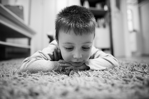 Cute little young boy lying on the floor in his bedroom