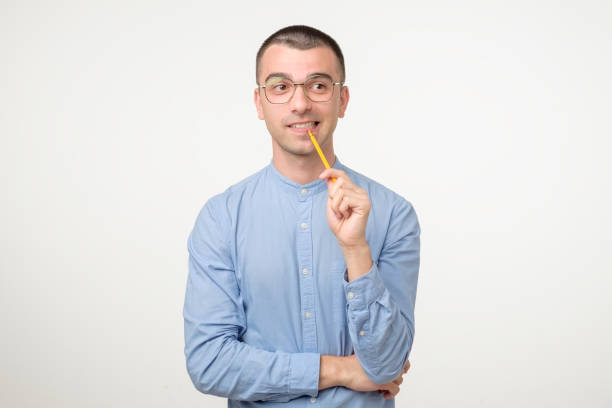 istock Young hispanic man in glasses is thinking about something with pencil 1213309640