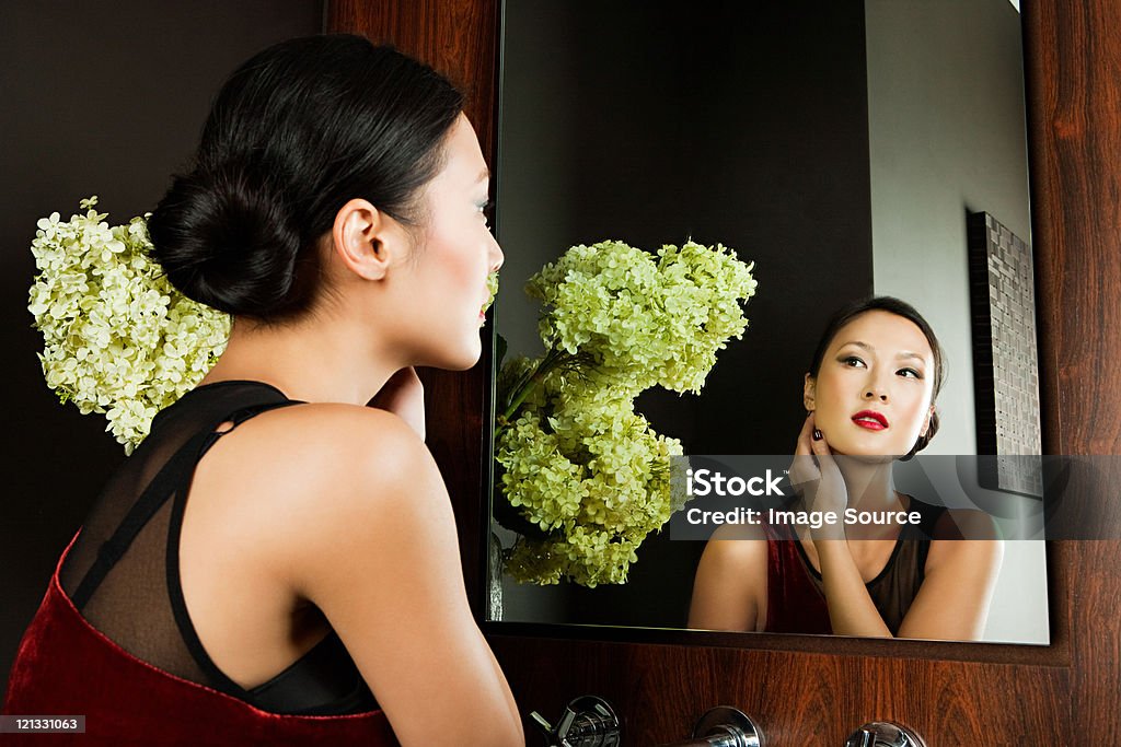 Young woman looking at reflection in mirror  25-29 Years Stock Photo