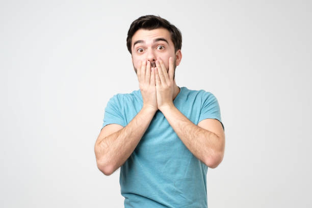 istock White hispanic man with hand over his mouth, stunned and speechless 1213317870