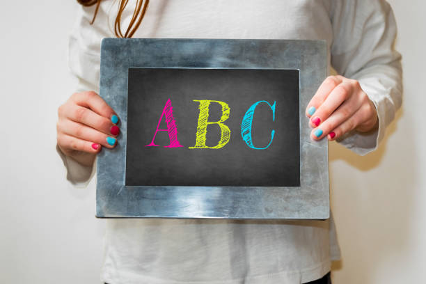 istock Child holding a blackboard with the text ABC in colorful letters 1213319847