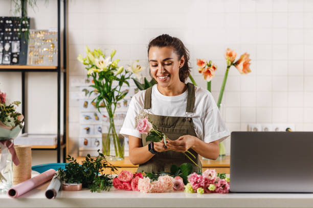 istock Smiling woman holding flowers at table arrangging a bouquet 1213320137