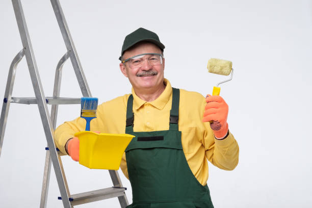istock Painter senior man at work with a paint roller, standing near ladder. 1213320216