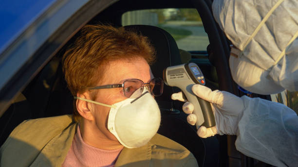istock CLOSE UP: Elderly woman wearing a facemask gets her body temperature checked. 1213321410