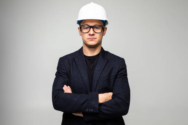 istock Confident man engineer wearing protective helmet holding hands crossed looking away isolated over white background. 1213329894
