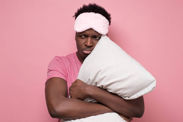 istock Low energy tired adult african man looking aside peeping through sleeping mask 1213331497